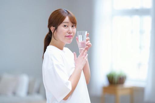 カメラ目線で水のグラスを持つ女性 女性,水,飲み物の写真素材