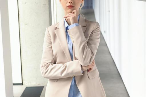 オフィスの通路で顎に手を当てて立つビジネスウーマン ビジネスウーマン,ビジネス,女性の写真素材
