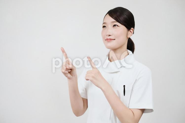 指さしのポーズをする白衣の女性  看護師,ナース,女性の写真素材