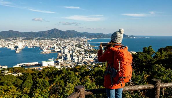 海の向こうを携帯で撮影する観光客の女性 海の向こうを携帯で撮影する観光客の女性の写真