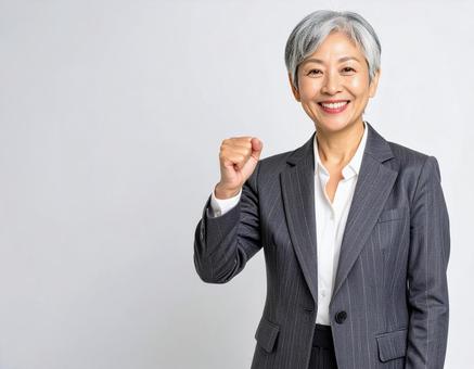 ガッツポーズをするスーツの白髪の女性 ガッツポーズをするスーツの白髪の女性の写真