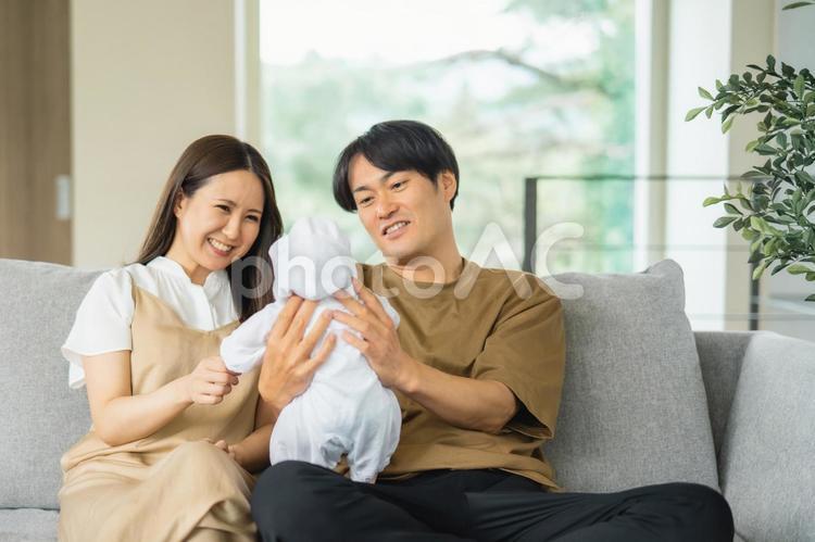 ソファで赤ちゃんを抱く男女 赤ちゃん,育児,新婚の写真素材