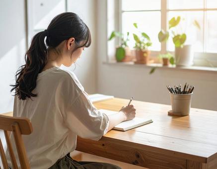 手帳に書き込みする若い女性 手帳に書き込みする若い女性の写真