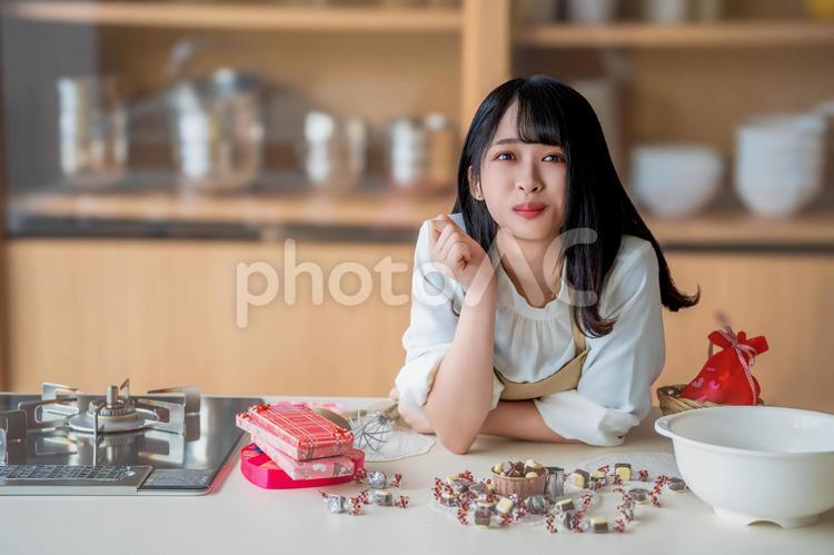 キッチンに肘を付いているエプロン姿の女性 バレンタイン,バレンタインデー,チョコの写真素材