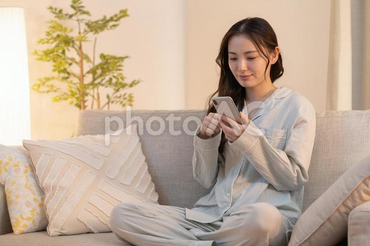 寝室で携帯を見る女性 女性,若い,夜の写真素材