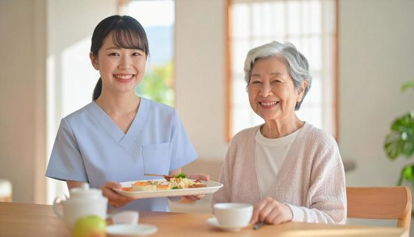 笑顔で食事を運ぶ女性介護士と高齢女性 笑顔で食事を運ぶ女性介護士と高齢女性の写真