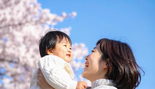 青空の下、子供を抱っこする母親 青空の下、子供を抱っこする母親の写真
