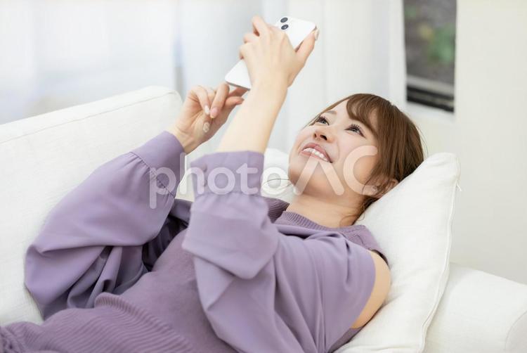 ソファーでスマホを使う女性 女性,人物,スマートフォンの写真素材