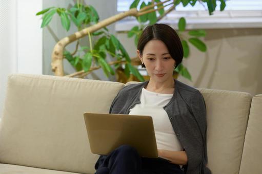 ソファで仕事をする日本人女性 ソファで仕事をする日本人女性の写真