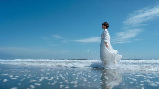 波打ち際を歩く白ワンピースの日本人女性 波打ち際を歩く白ワンピースの日本人女性の写真