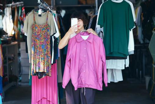古着屋で洋服を持って写真を撮る若い女性 古着屋で洋服を持って写真を撮る若い女性 古着,サブカル,サブカルチャーの写真素材