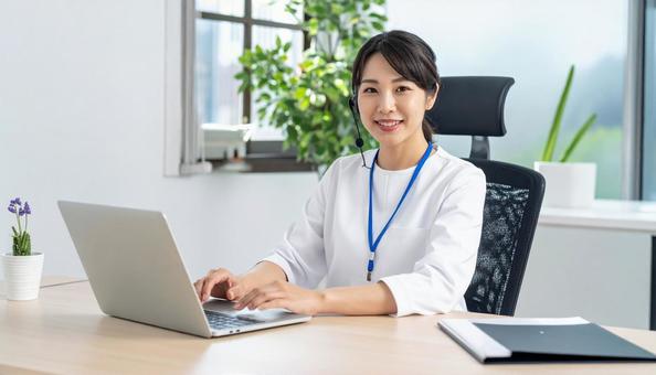 パソコンに向かって話す女性 パソコンに向かって話す女性の写真