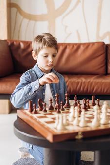 ソファテーブルでチェスをしている男の子 ソファテーブルでチェスをしている男の子の写真