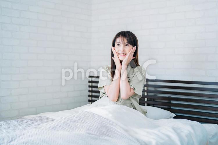 ベッドでお肌を触るミドル世代の女性（笑顔） 睡眠,スキンケア,美容の写真素材