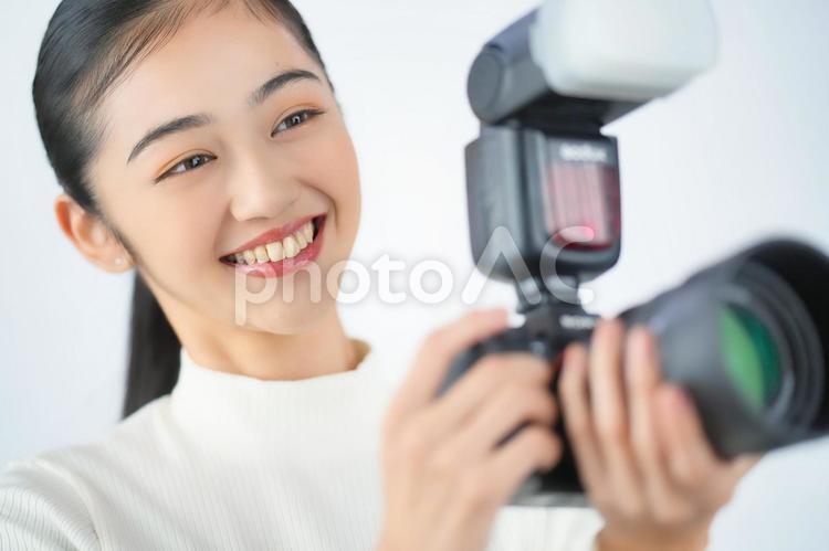 クリップオンストロボのついたカメラを構える女性（白背景） 大人,大学生,社会人の写真素材