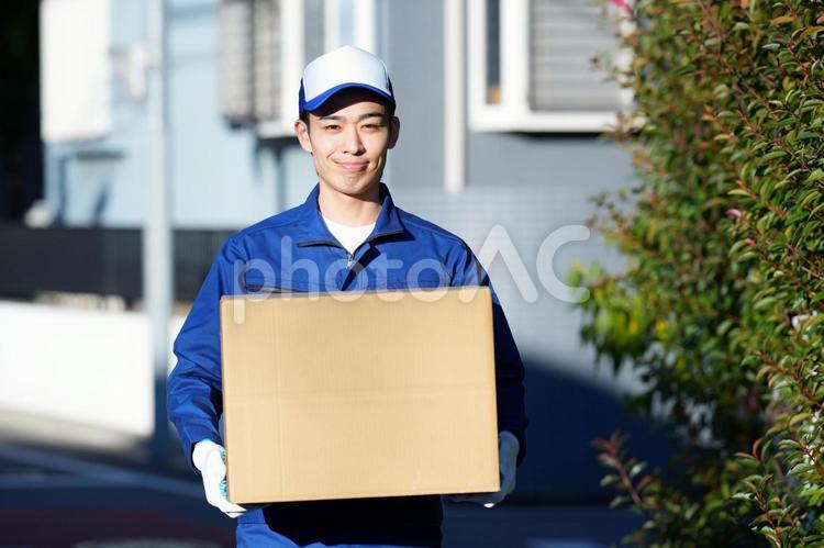 屋外で段ボール箱を持って立っているカメラ目線の引っ越し作業員 引っ越し,男性,日本人の写真素材