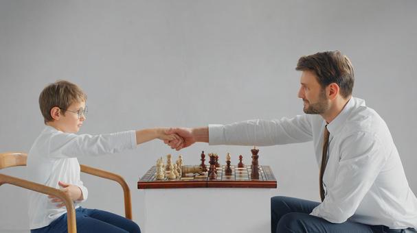 チェスの上で握手している親子(グレー背景) チェスの上で握手している親子(グレー背景) チェス,親子,お父さんの写真素材