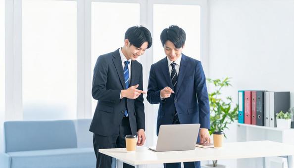 パソコンを見ながら打ち合わせをする男性 パソコンを見ながら打ち合わせをする男性の写真