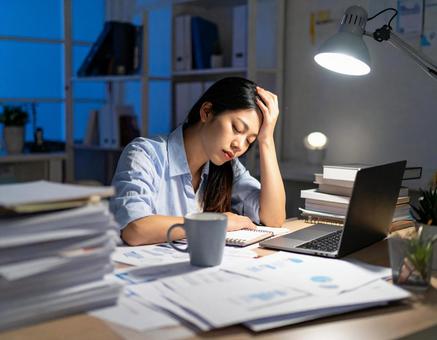 深夜残業に疲れる女性の写真