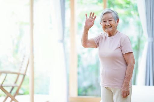 窓際で手を振る高齢女性 女性,手を挙げる,手を振るの写真素材