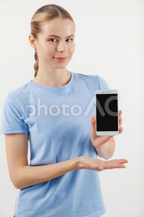 スマホ画面を見せるように持つカメラ目線の女性 女性,スマートフォン,画面の写真素材