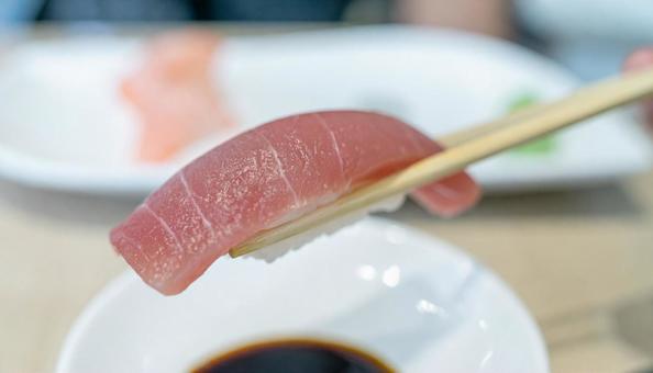 マグロ寿司を箸でつまむ マグロ寿司を箸でつまむの写真