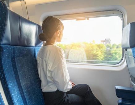 新幹線で窓を眺めている女性の写真