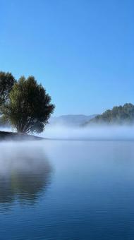 水面に映る山々が美しい、幻想的な朝の湖の写真