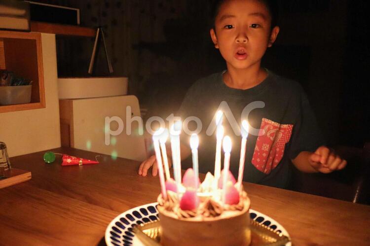 誕生日パーティー　ケーキのロウソクを消す男の子　ー　食べ物　イベント　 男の子,誕生日,ケーキの写真素材
