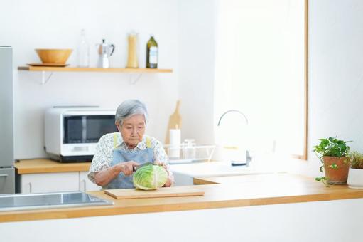 真剣な顔でキャベツを切る高齢女性 女性,キャベツ,野菜の写真素材