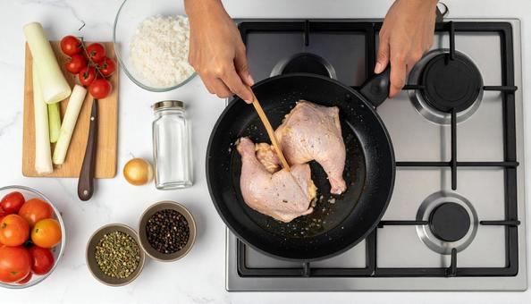 フライパンで鶏肉を炒める女性の手 フライパンで鶏肉を炒める女性の手の写真