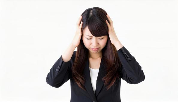 頭を抱えて悩むスーツ姿の若い女性 頭を抱えて悩むスーツ姿の若い女性の写真