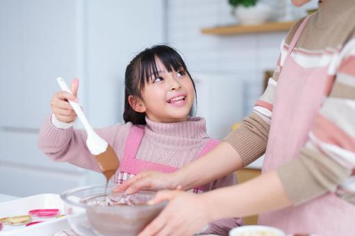 ピンクのエプロンを着た少女のお菓子作り 女の子,チョコレート,ヘラの写真素材
