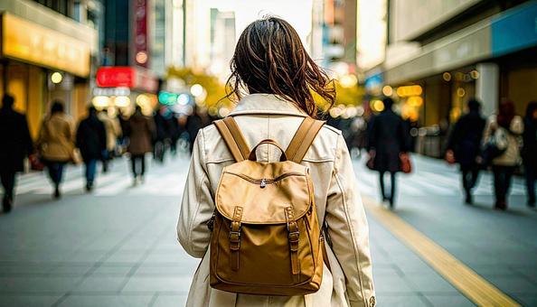街中を歩いていくリュック姿の女性の後ろ姿 街中を歩いていくリュック姿の女性の後ろ姿の写真