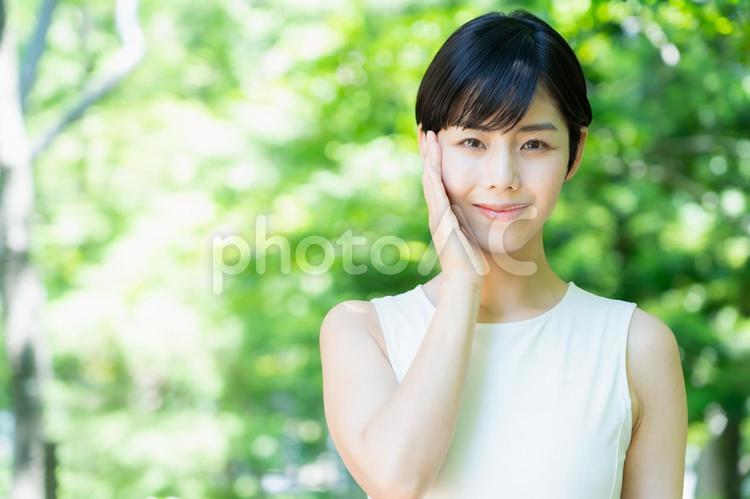 緑の中でスキンケアをする若い女性 スキンケア,ビューティー,女性の写真素材