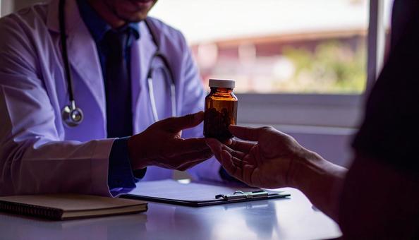 患者に対して簡単な服薬指導を行う男性医師 患者に対して簡単な服薬指導を行う男性医師の写真