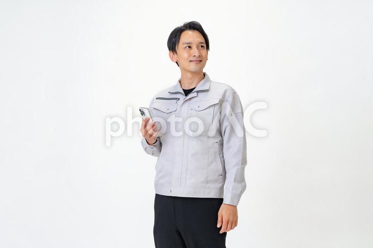 携帯を見る作業着を着た男性 日本人,点検,保守点検の写真素材