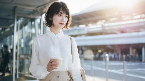 オフィス街でコーヒーを持つ若い女性 オフィス街でコーヒーを持つ若い女性の写真