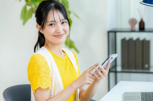 スマホを操作する若い女性 ビジネスウーマン,若い女性,笑顔の写真素材