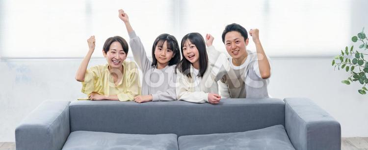 ソファでガッツポーズをする家族 子育て,育児,リビングルームの写真素材