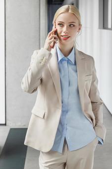 オフィスの通路でスマートフォンで電話するビジネスウーマン ビジネスウーマン,ビジネス,女性の写真素材