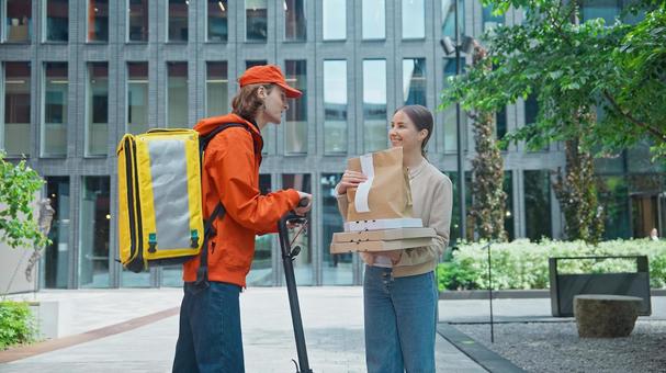 ビルの前でフードデリバリーを受け取る女性の写真