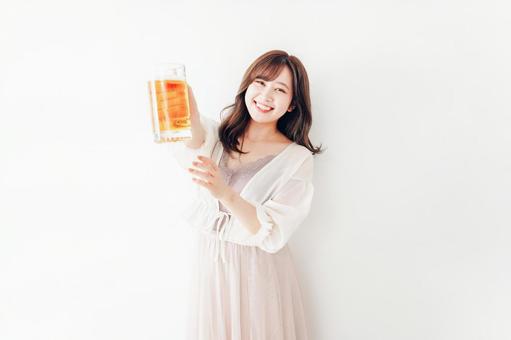ジョッキで乾杯をする若い女性 ジョッキで乾杯をする若い女性 新年会,飲酒,ストレス解消の写真素材