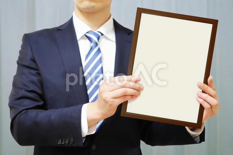 「白紙の額縁」を発表する男性-水色のカーテン背景 白紙,人物,男性の写真素材