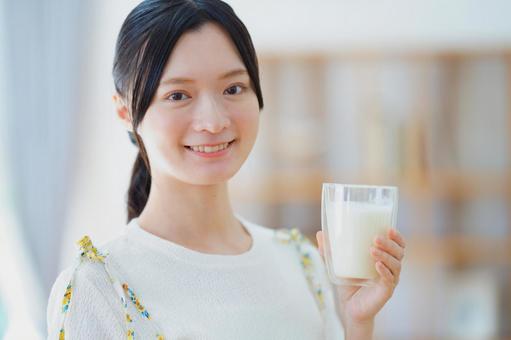 片手で牛乳のコップを持ちカメラ目線の女性 女性,牛乳,コップの写真素材