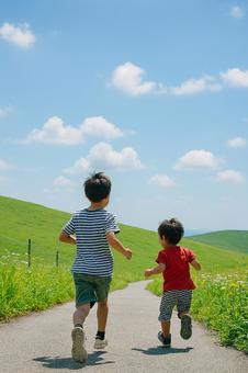 自然の野原を走る子供達の後ろ姿 自然の野原を走る子供達の後ろ姿の写真