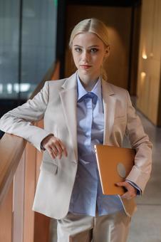 オフィスの廊下の手すりに肘をかけて立つ女性 ビジネスウーマン,ビジネス,女性の写真素材