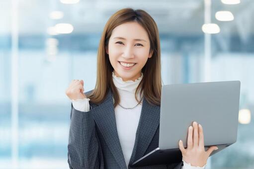 パソコンを持ってガッツポーズをする女性 女性,ガッツポーズ,笑顔の写真素材