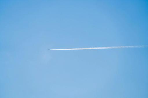 青空に伸びる飛行機雲の写真