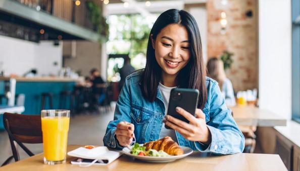 カフェで携帯を使う若いビジネスウーマン カフェで携帯を使う若いビジネスウーマン の写真